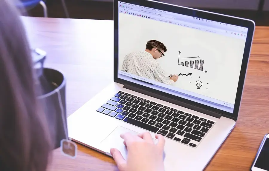 Person watching an online lesson about charts and financial analysis on a laptop.