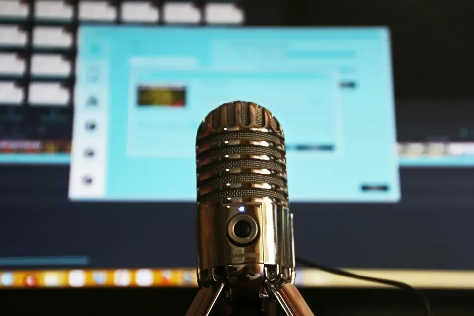 Podcast microphone in front of a computer screen.